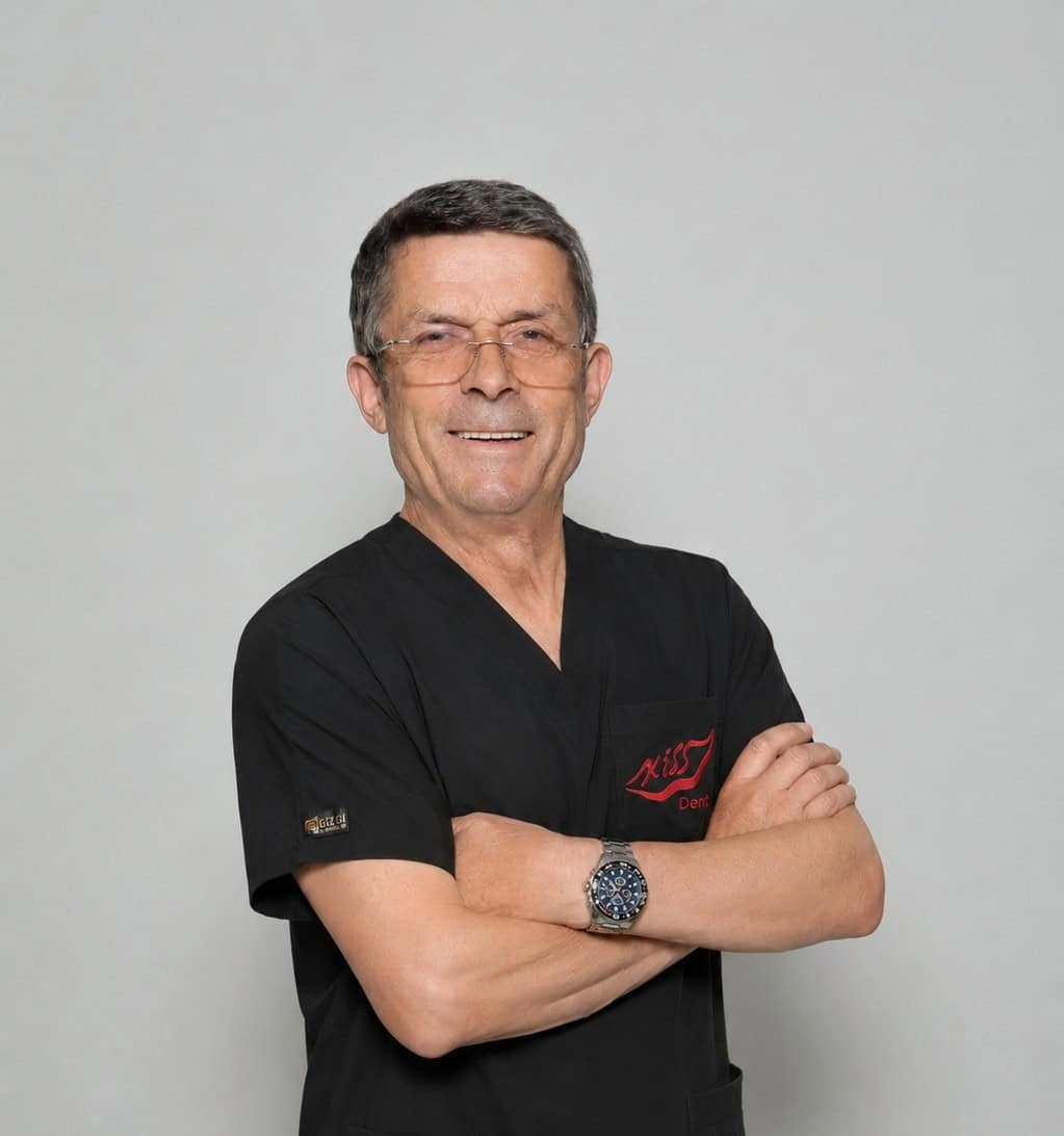 Dr. Albert Gjata in dental clinic wearing black scrubs and glasses.