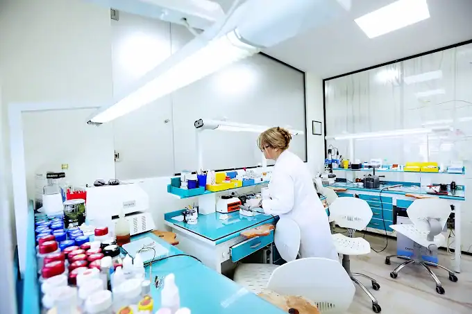 Tecnico dentale che lavora in un laboratorio odontotecnico high-tech con vari materiali e strumenti dentali.