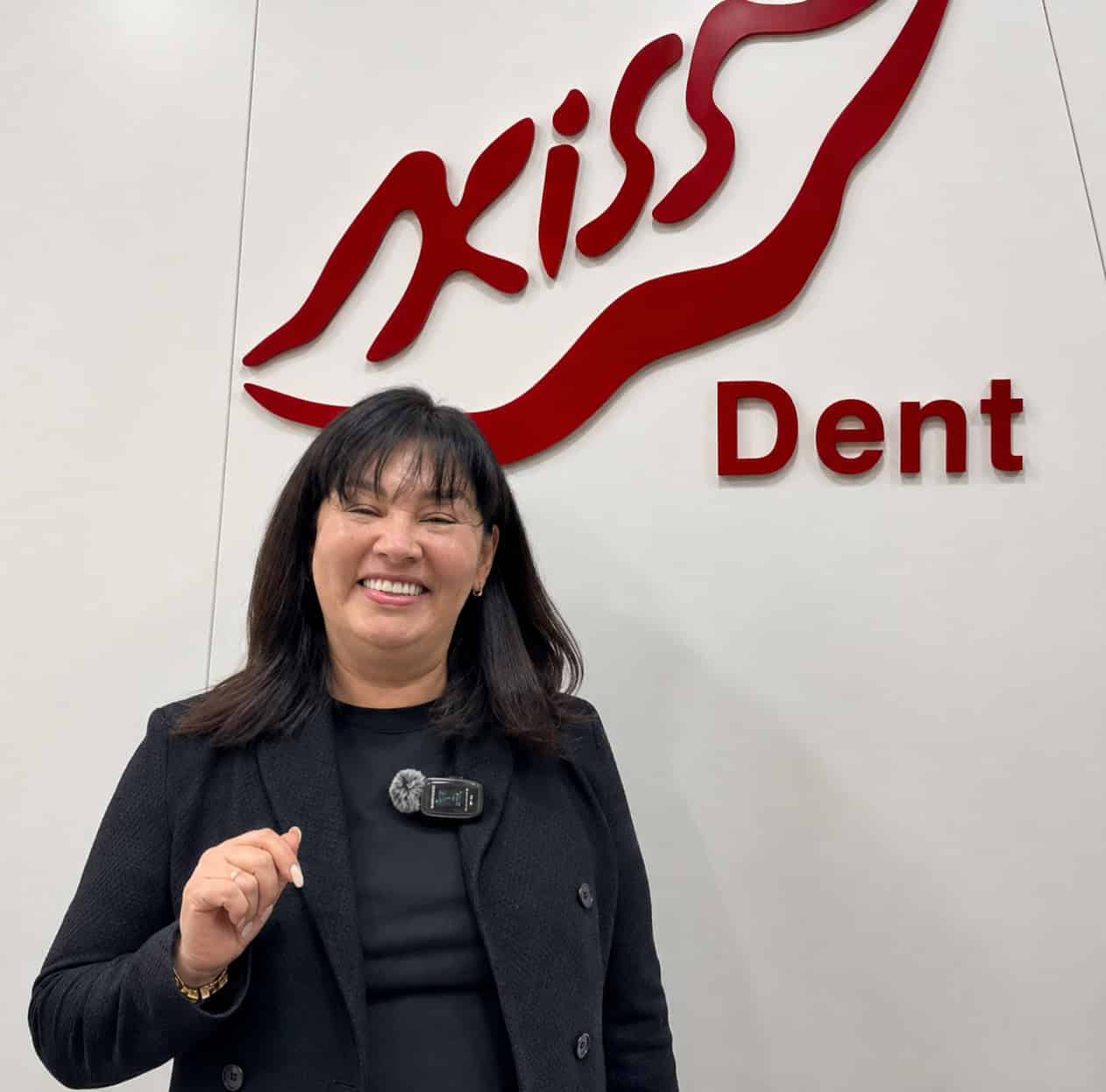 Reception area sign at Kiss Dental Clinic with a smiling woman in front.